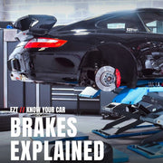 A black sports car is shown raised on a hydraulic lift in a garage setting, with the rear wheel removed to expose the brake rotor and caliper. Large overlaid text reads 'EZ KNOW YOUR CAR BRAKES EXPLAINED' with a tire graphic at the bottom.