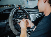 Person working on a car's steering wheel inside a vehicle